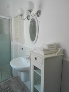 uma casa de banho branca com um lavatório e um espelho em Ildi's Guest House em Seriate