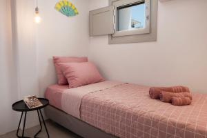 Dormitorio pequeño con cama rosa y mesa pequeña en Secret Khora en Mykonos ciudad