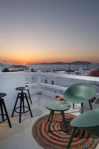 a rooftop patio with tables and chairs and the sunset at Secret Khora in Mýkonos City