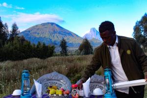 Under Volcanoes View Guest House في Nyarugina: رجل واقف امام طاوله فواكه