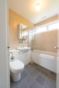 a bathroom with a toilet and a sink and a tub at Spacious Family Bungalow with Garden for up to 7 in Epsom