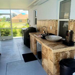 ein Badezimmer mit einer Theke mit einem Waschbecken und einem Fenster in der Unterkunft Areca Palms Cape Coral with HEATED POOL in Cape Coral