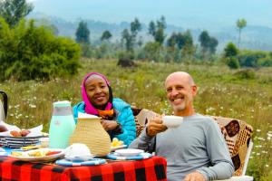 un hombre y una mujer sentados en una mesa con un plato de comida en Under Volcanoes View Guest House, en Nyarugina