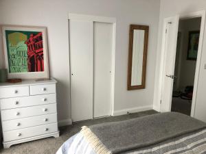 1 dormitorio con cama, tocador y espejo en Woodcliff en Birkenhead