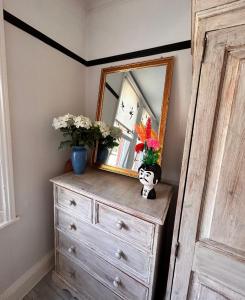 a dresser with a mirror and flowers on it at Antiquated house in Scarborough