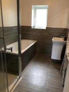 a bathroom with a bath tub and a sink at Woodcliff in Birkenhead