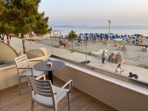 Deluxe Residence في دوريس: شرفة مع طاولة وكراسي وإطلالة على الشاطئ