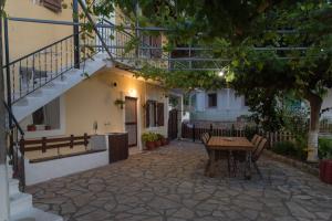 een patio met een tafel en stoelen voor een gebouw bij metaxas house in Mikros Gialos
