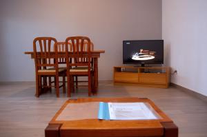 salon ze stołem, krzesłami i telewizorem w obiekcie Apartamentos Monte da Rosa w mieście Vila Nova de Milfontes