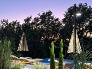 2 sombrillas y sillas junto a una piscina en Hotel Restaurant Natyra e Qetë, en Lezhë