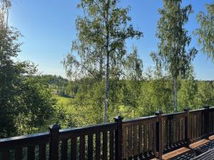 a wooden deck with a view of a field and trees at Villa Breikki Himos - Alpha & Bravo Incl WiFi, Sauna, Jacuzzi for extra fee in Jämsä