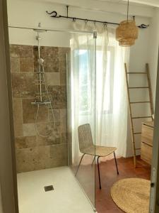 - une douche en verre dans une chambre avec une chaise dans l'établissement L’Attellu, à Feliceto