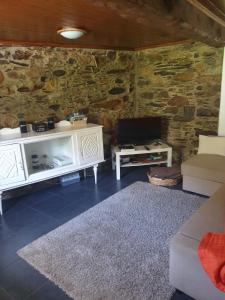 uma sala de estar com mobiliário branco e uma parede de pedra em Casa da Eduardinha em Góis