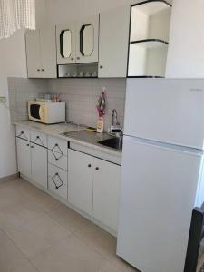 una cucina con armadietti bianchi e frigorifero bianco di Chez Hana apartment in beautiful city of Permet a Përmet