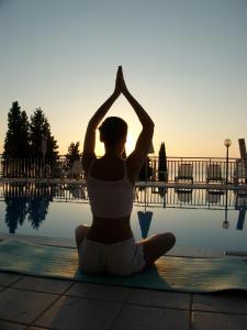 a woman sitting in a yoga pose in front of a pool at Aronis Apartments in Benitses