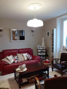 ein Wohnzimmer mit einem roten Sofa und einem Tisch in der Unterkunft Petit nid des années 30 sur les hauts de Morlaix in Morlaix