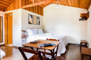 a bedroom with a bed and a wooden table with a table at Chalés Terra dos Sonhos - Monte Verde in Monte Verde