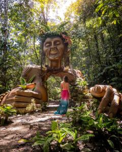 una mujer parada frente a una estatua gigante en el bosque en ECO HOTEL RIO DE ORO en San Rafael