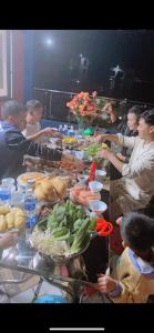 een groep mensen die rond een tafel vol eten staan bij Hùng Trang Hotel Tam Đảo 1 in Tam Ðảo