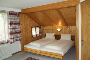 ein Schlafzimmer mit einem Bett in einem Holzzimmer in der Unterkunft Hotel Pension Spycher in Kandersteg