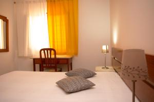 sypialnia z łóżkiem, krzesłem i oknem w obiekcie Apartamentos Monte da Rosa w mieście Vila Nova de Milfontes