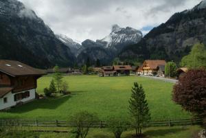 ein großes grünes Feld mit Bergen im Hintergrund in der Unterkunft Hotel Pension Spycher in Kandersteg