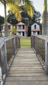 普拉多斯的住宿－Chalés Jatobá，一座木桥,通往一座棕榈树的房子