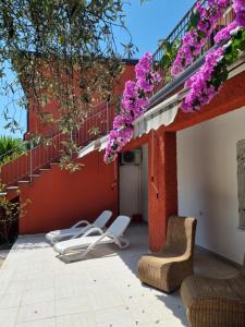 un patio con sillas blancas y flores púrpuras en Borgo Antico Apartments, en Toscolano Maderno