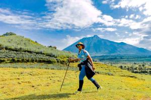 a woman walking on a hill with mountains in the background at Under Volcanoes View Guest House in Nyarugina