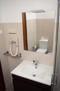 W łazience znajduje się umywalka i lustro. w obiekcie Apartamentos Monte da Rosa w mieście Vila Nova de Milfontes