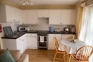 een keuken met witte kasten en een tafel met stoelen bij St Margaret's Bay Holiday Let in St Margarets at Cliff