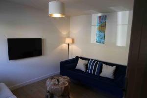 sala de estar con sofá azul y TV de pantalla plana en King's Cottage, Wootton, Nr Woodstock., en Wootton