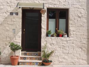 a house with a black door and a window and potted plants at Monolocale l'Abbraccio in Ragusa