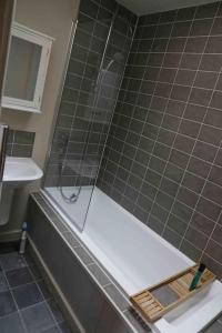 a bathroom with a shower with a tub and a sink at King's Cottage, Wootton, Nr Woodstock. in Wootton