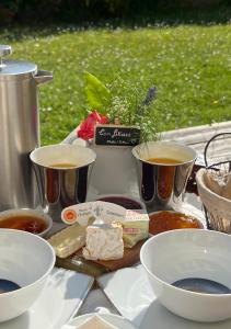 una mesa con tazones de comida y tazas de café en Les Nord’mandines, en Trouville-sur-Mer