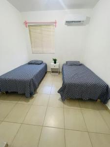 Habitación con 2 camas, paredes blancas y suelo de baldosa. en Renta vacacional, en Playa del Carmen