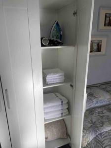 a white closet with folded towels and a bed at Lovely Studio in Dublin City Centre in Dublin