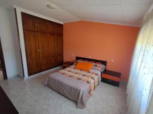 1 dormitorio con cama y pared de color naranja en Alquiler vacacional. A de Casas, en Sanxenxo