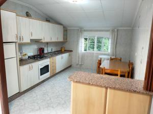 uma cozinha com armários brancos e uma mesa em Alquiler vacacional. A de Casas em Sanxenxo