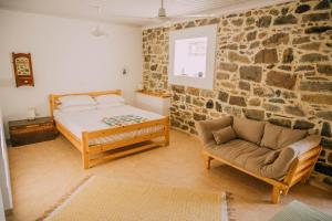 1 dormitorio con cama, sofá y pared de piedra en The apricot tree studio, en Samotracia