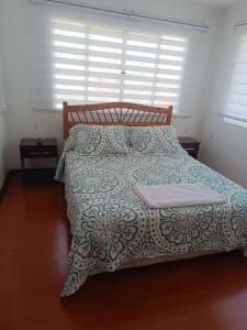 a bedroom with a bed with a blue and white comforter at Hospedaje Nuevo Amanecer in Antofagasta