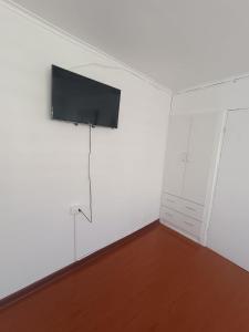 um quarto branco com uma televisão de ecrã plano na parede em Hospedaje Nuevo Amanecer em Antofagasta