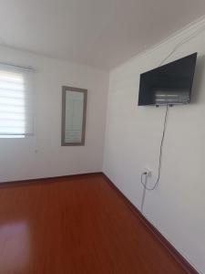 um quarto branco com uma televisão na parede em Hospedaje Nuevo Amanecer em Antofagasta