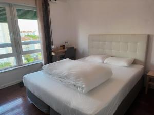 a bedroom with a bed with white sheets and a window at Cozy Room near Metro & Airport in Lisbon