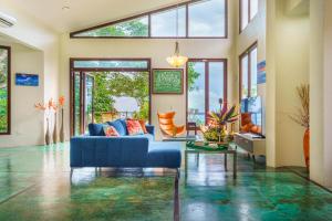 a living room with a blue couch and glass windows at Colores del Viento - by Pura Villas in Uvita +34 photos