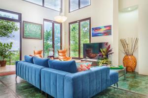 a large blue couch in a living room with windows at Colores del Viento in Uvita