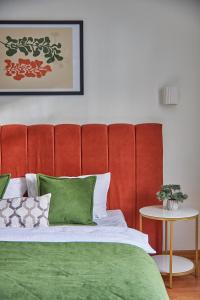 a bed with a red padded headboard and green pillows at Best Apartments on Kyryla & Mefodia in Mukacheve