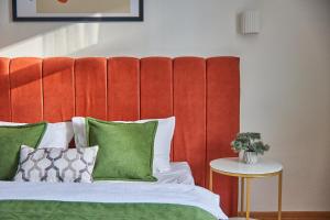 łóżko z czerwonym zagłówkiem i zielonymi poduszkami w obiekcie Best Apartments on Kyryla & Mefodia w mieście Mukaczewo