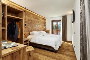 1 dormitorio con 1 cama y pared de madera en Hotel Garni dello Sportivo, en Madonna di Campiglio