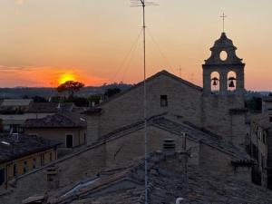 un tramonto su un edificio con torre dell'orologio di - Chalet Urbano - a Fano
